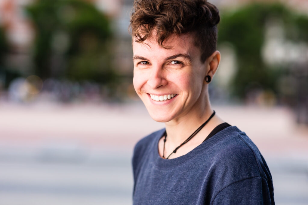 Person with short hair smiling outside