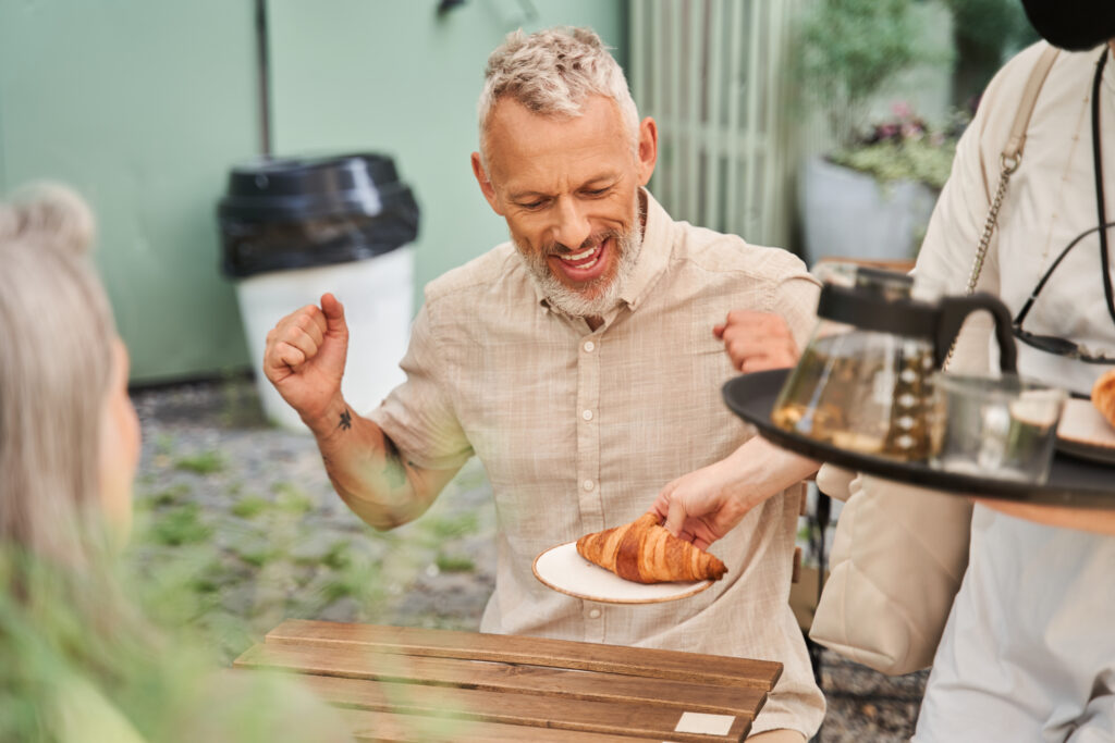 Man at a cafe getting a croissant
