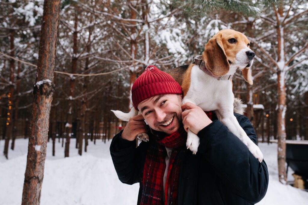Man outside in the winter with a dog on his shoulders