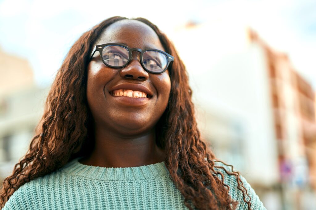 Young black woman smiling happy wearing glasses at the city