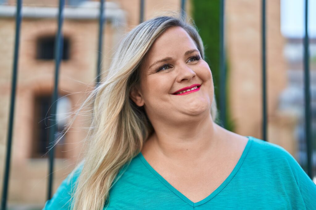 woman in a blue shirt standing outside smiling