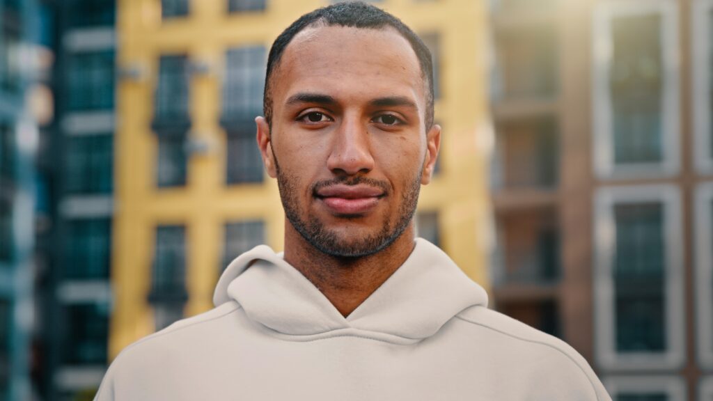 Young man standing outside in front of apartment buildings