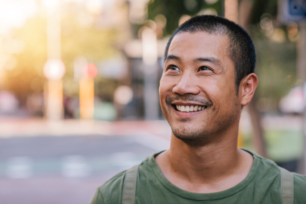 Man smiling while standing outside in a park