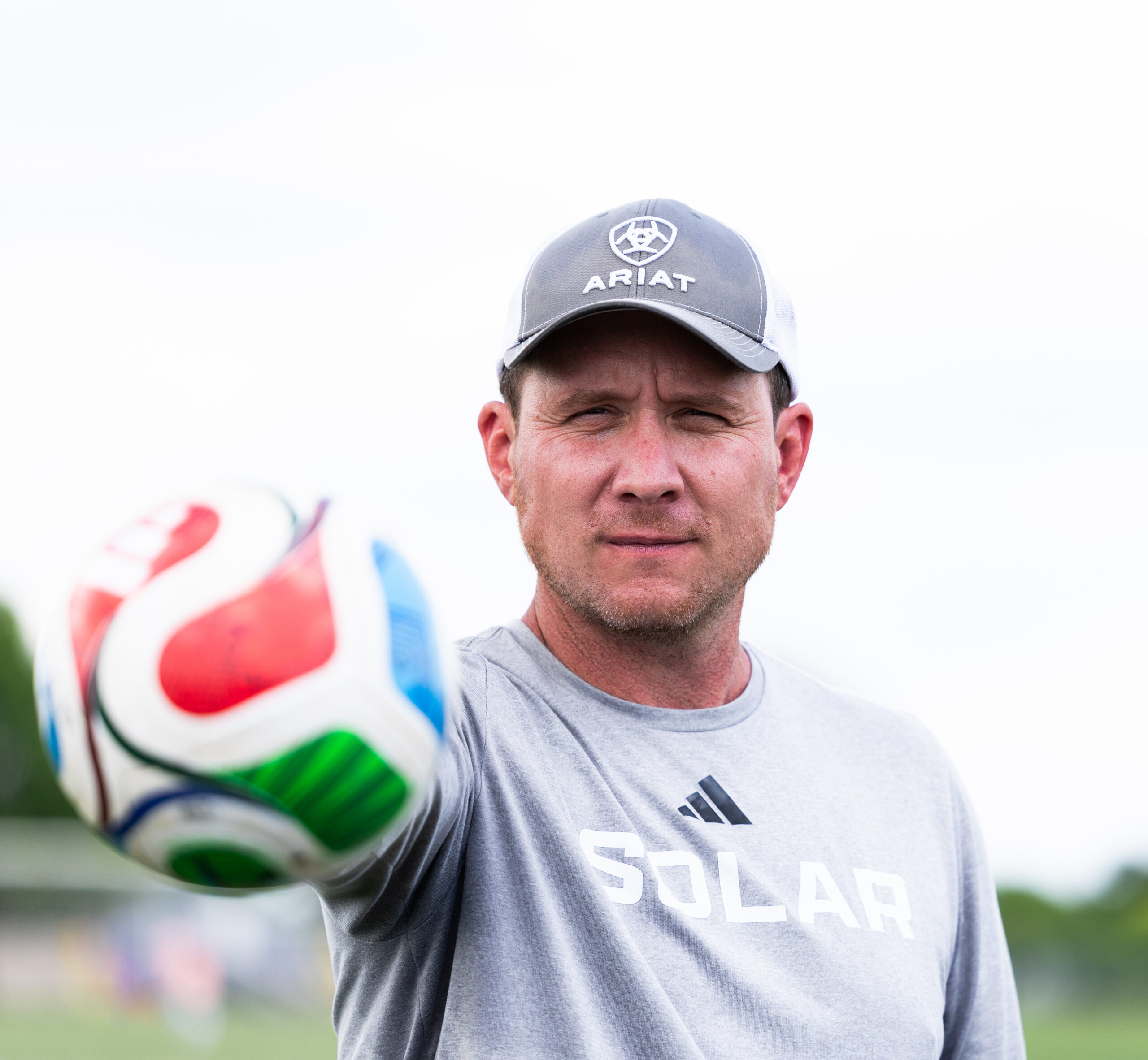 Soccer coach holding a ball up to the camera