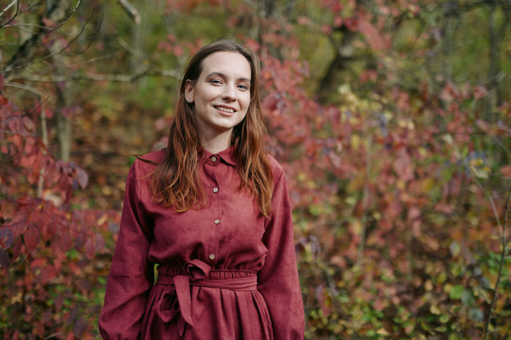 Woman with long hair standing in a field wearing a red dress