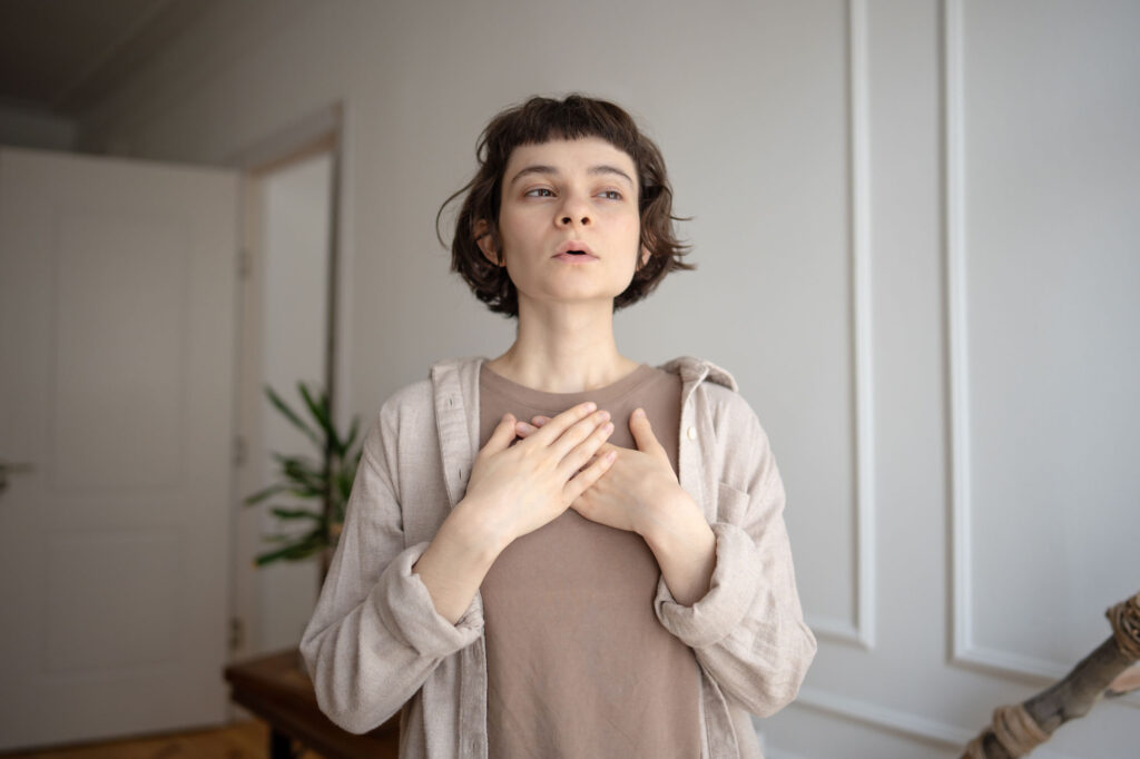 Woman with medium length hair with her hands on her chest