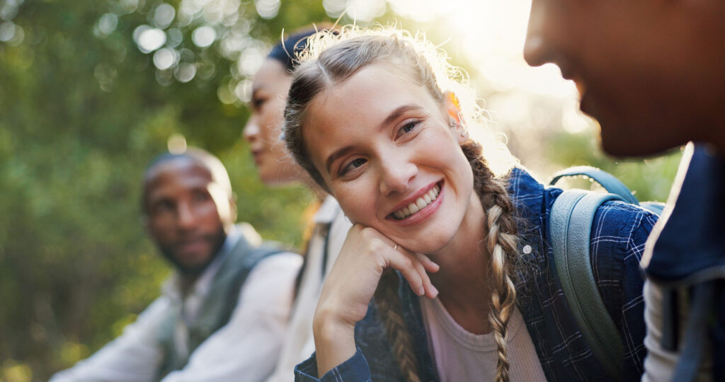 Woman with a backpack smiling sitting next to two men