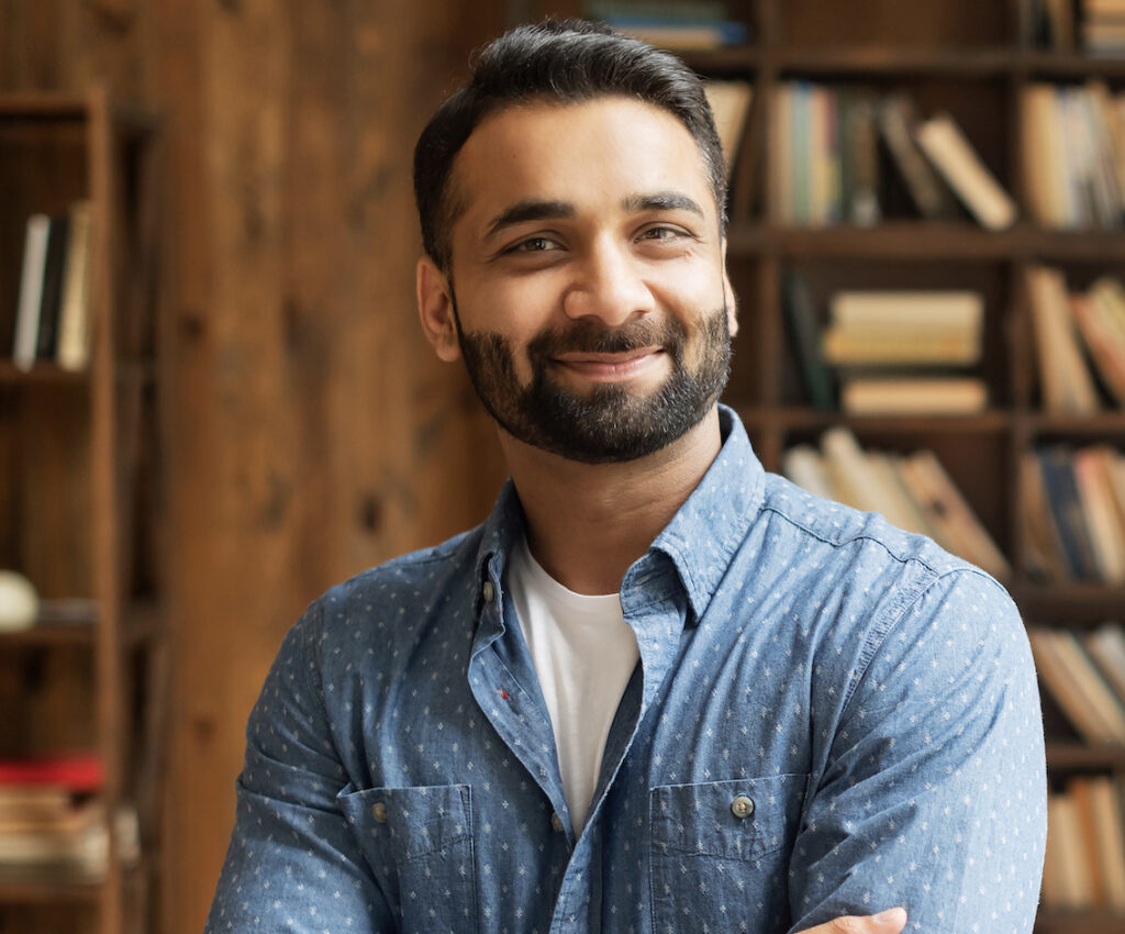 Man in a blue shirt standing in a library smiling