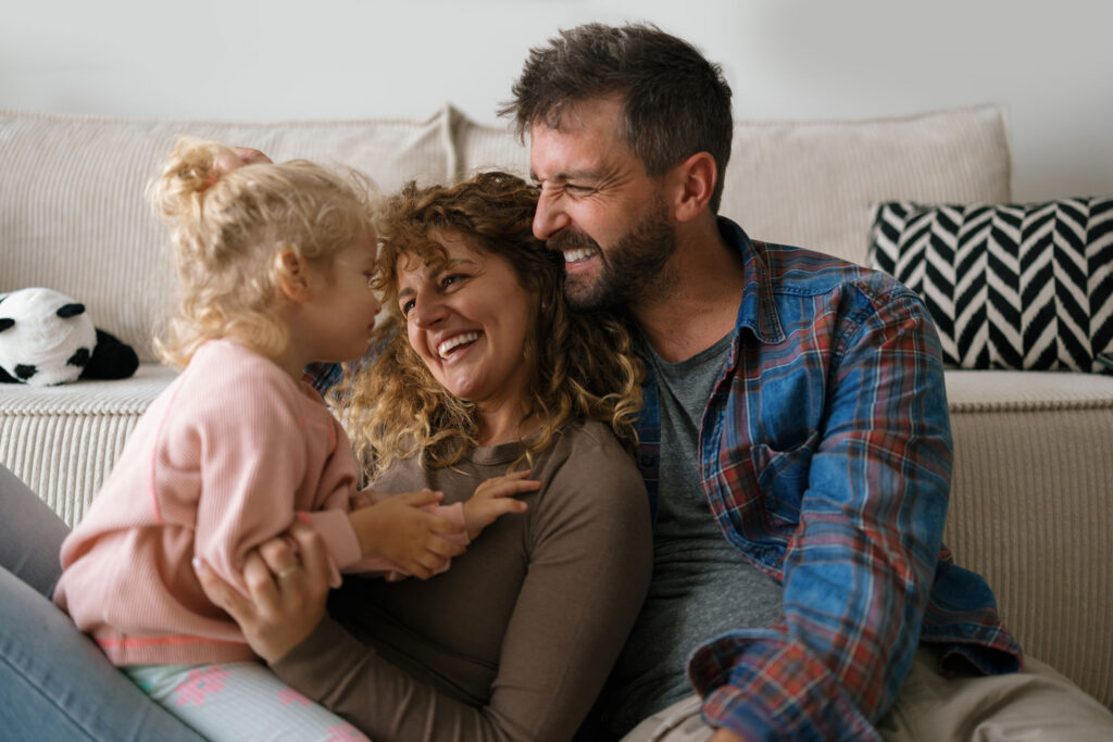 Mother Father and Daughter on couch smiling and laughing