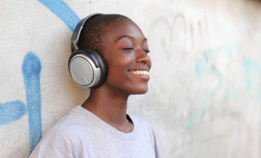 Woman leaning against the wall wearing headphones and smiling